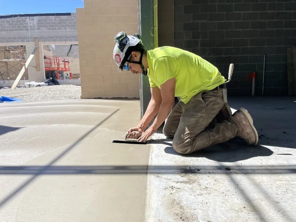Masonry worker finishing a concrete floor on a construction site